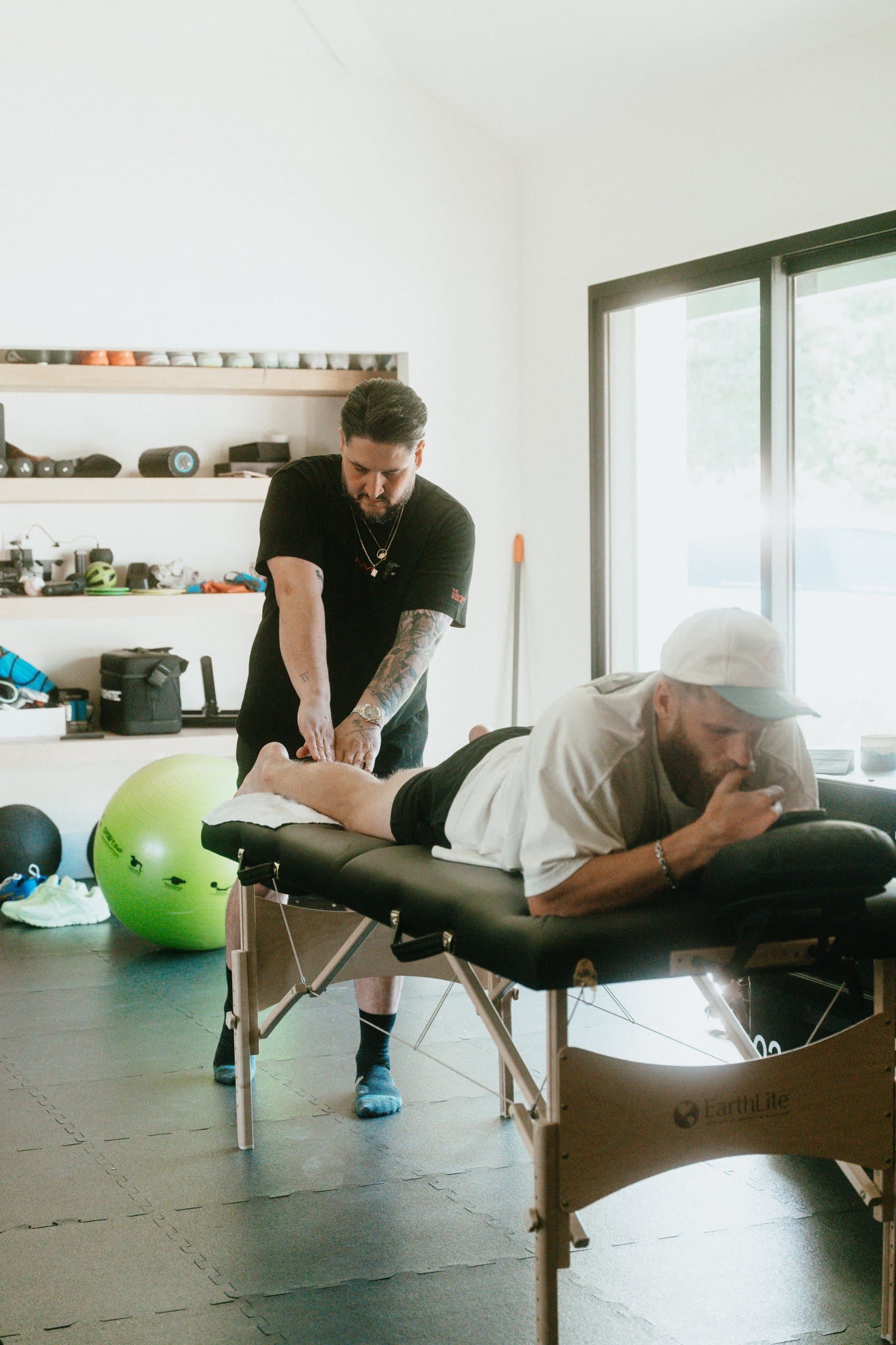 An MMVP therapist working on an athlete on a treatment table in a bright studio