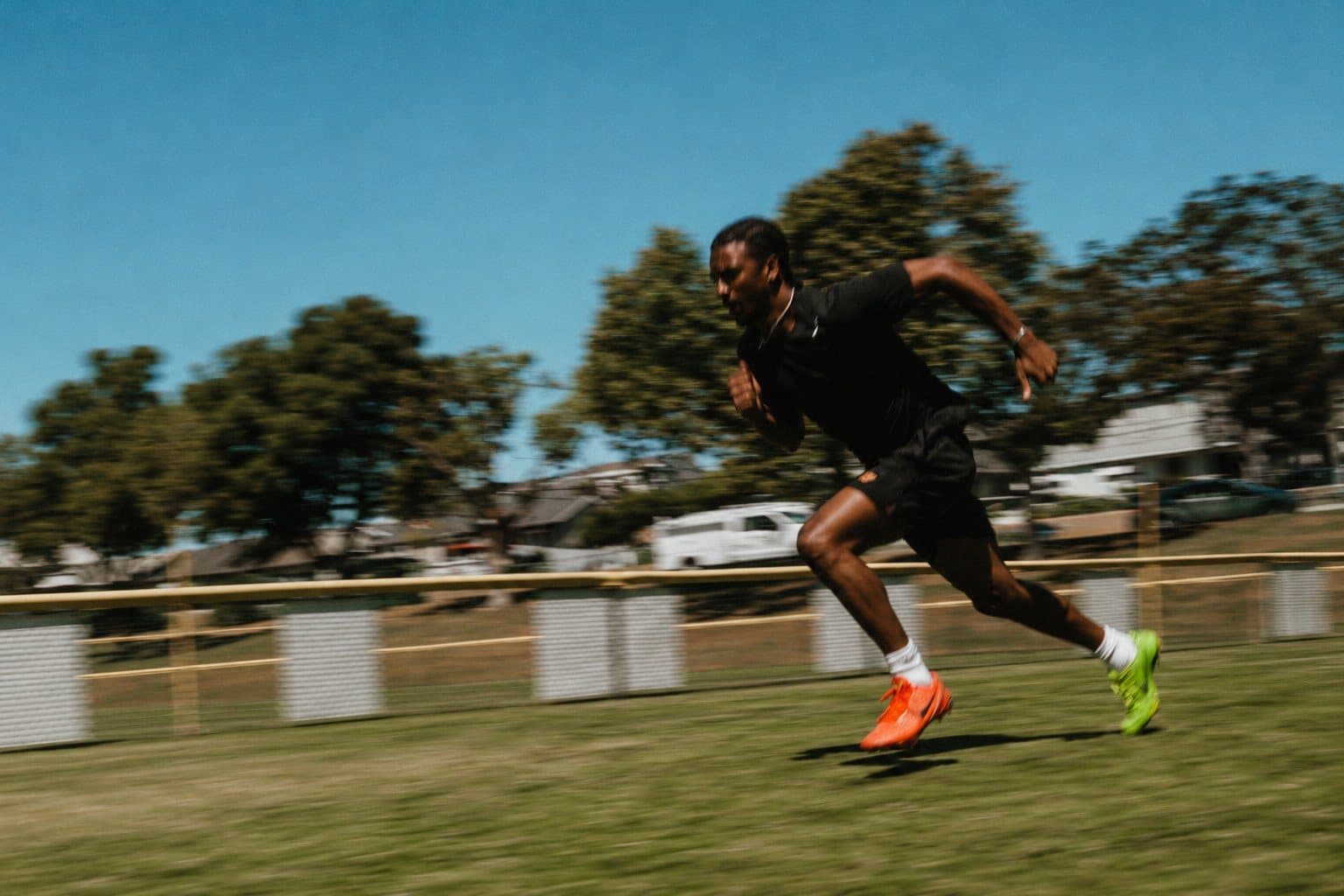 An athlete sprinting across a grass field in the sun