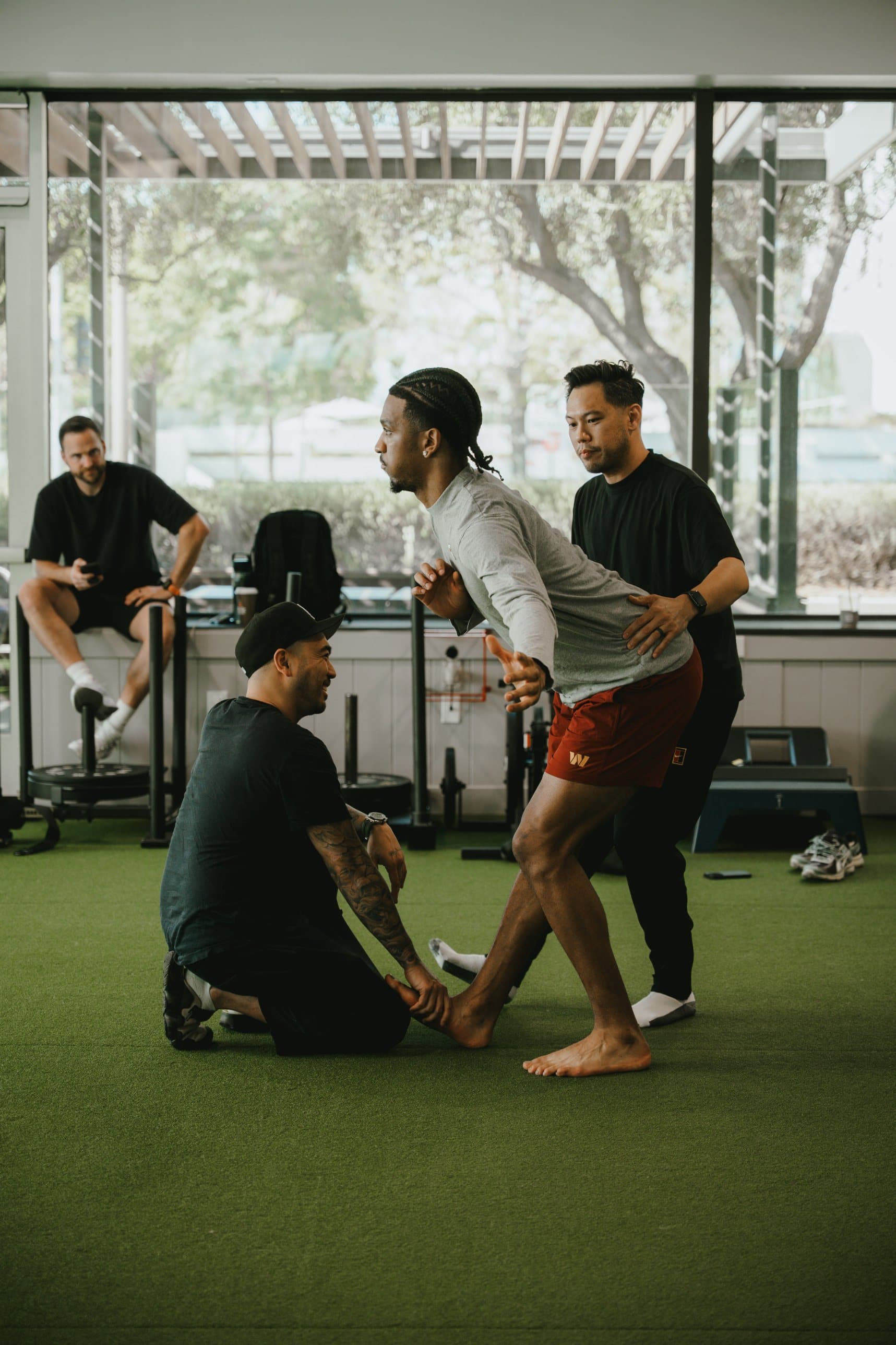 MMVP coaches guiding an athlete through a movement assessment on turf